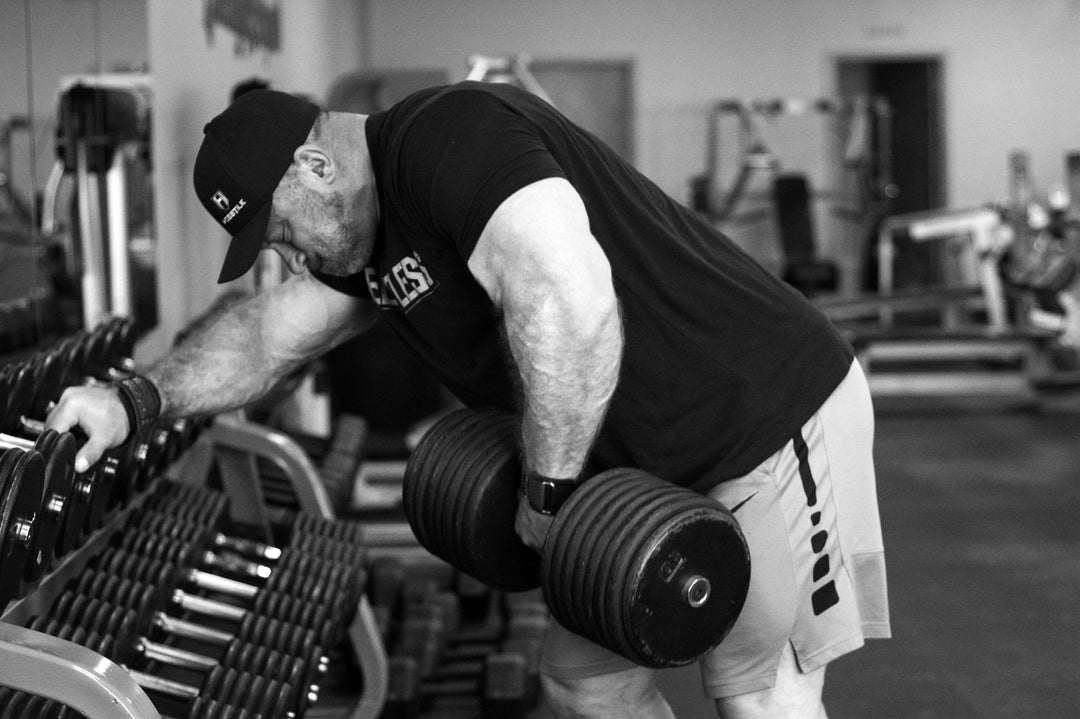 Bodybuilder Justin Harris in gym doing heavy dumbbell rows
