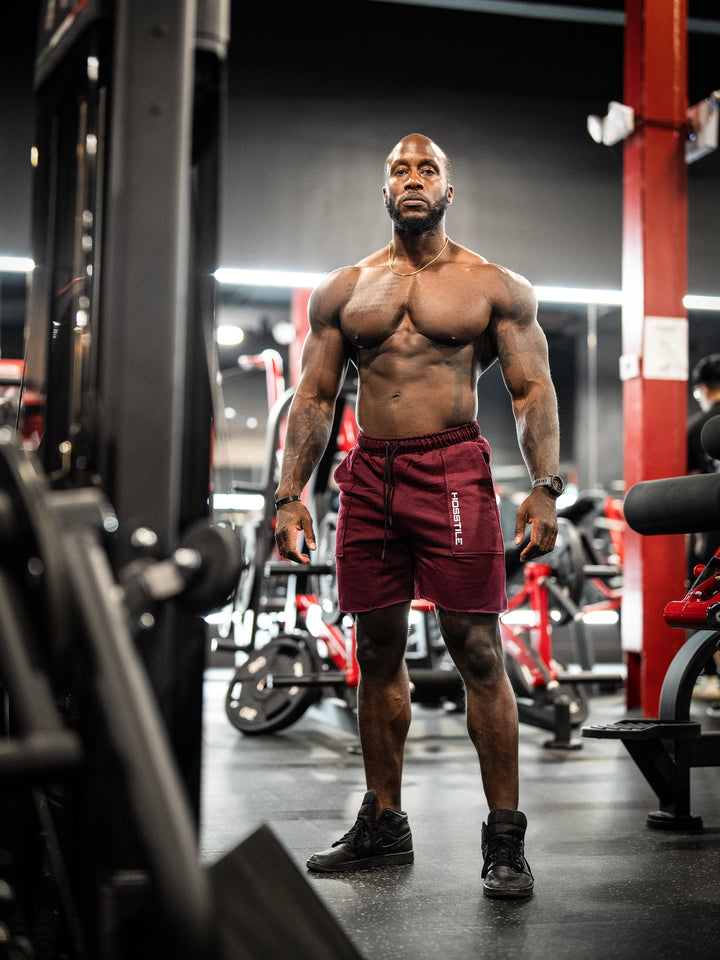 Bodybuilder wearing the Classic Raw shorts#color_cherry