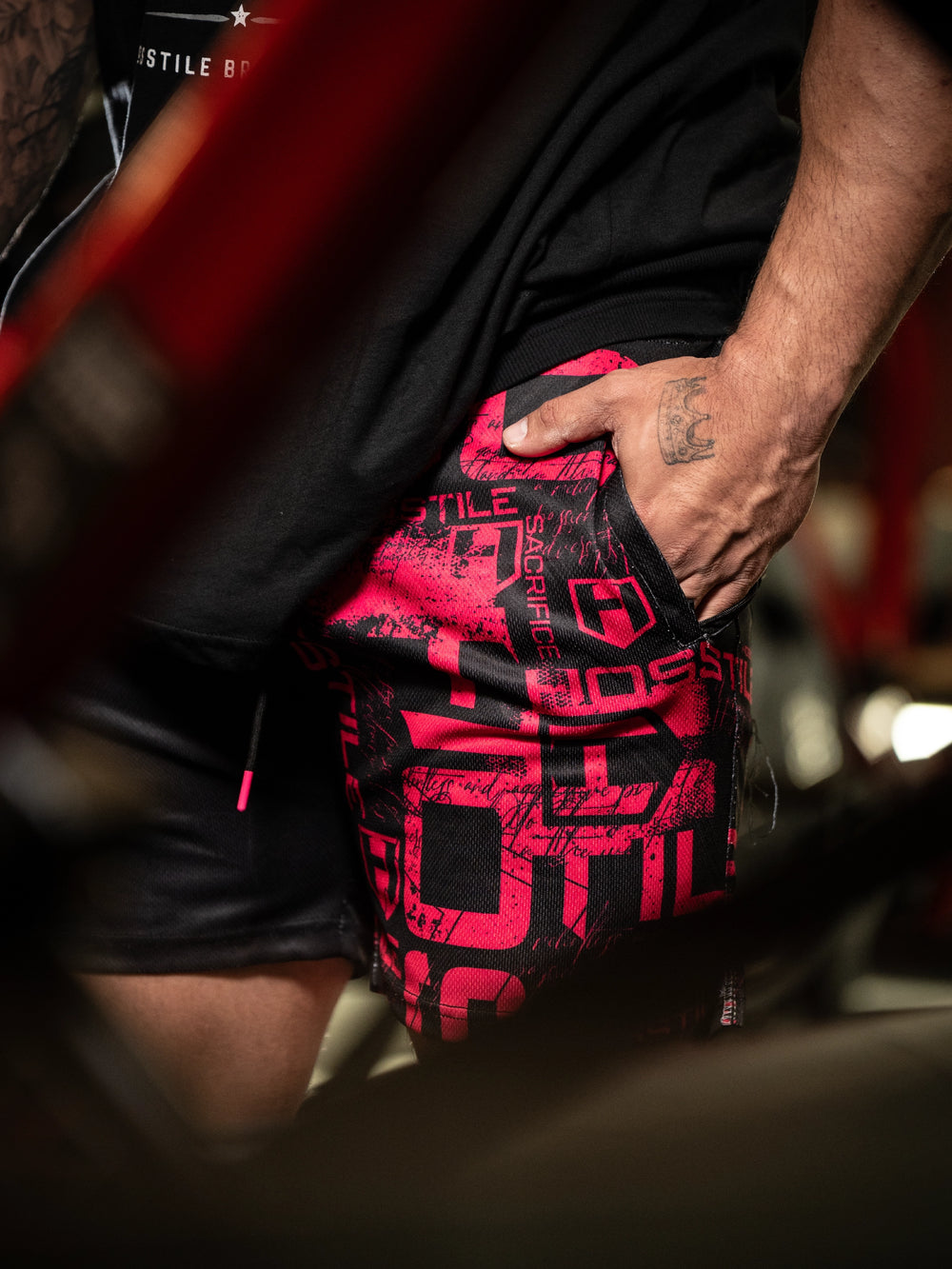 Person wearing black shorts with red and white pattern, holding a red bag#color_black