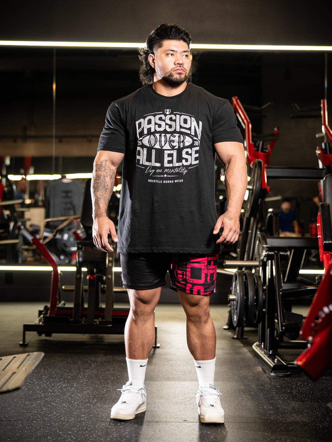Man in a gym wearing a black t-shirt with text and red shorts#color_black