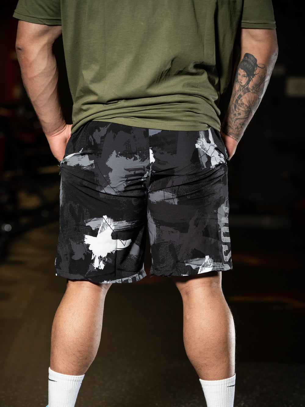 Person wearing camouflage shorts and a green shirt with a dark background#color_onyx