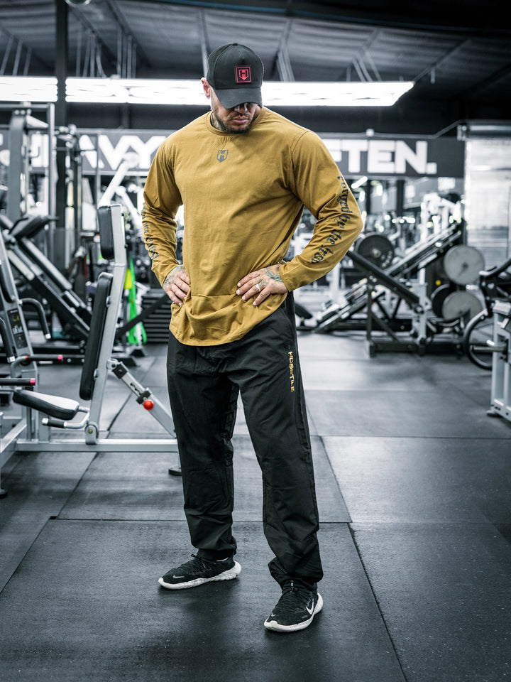 Bodybuilder Ben Chow wearing a long-sleeve shirt and black pants in a gym setting#color_black
