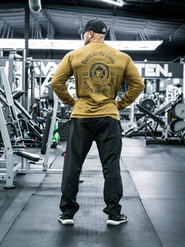 Bodybuilder Ben Chow wearing a long-sleeve shirt and black pants in a gym setting#color_black