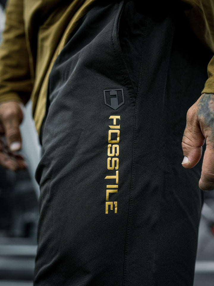 Bodybuilder Ben Chow wearing a long-sleeve shirt and black pants in a gym setting#color_black