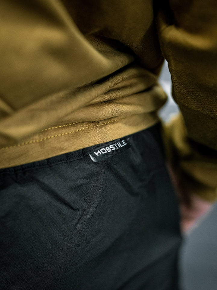 Bodybuilder Ben Chow wearing a long-sleeve shirt and black pants in a gym setting#color_black