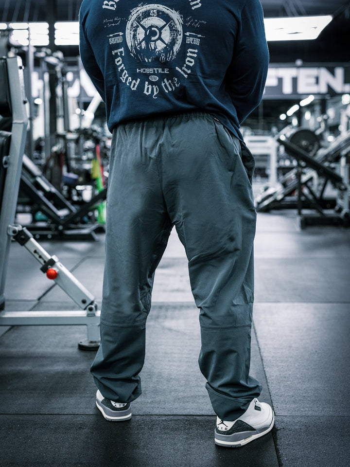 IFBB Pro Bodybuilder Martin Fitzwater wearing a long-sleeve shirt and dark grey pants in a gym setting#color_dark-grey