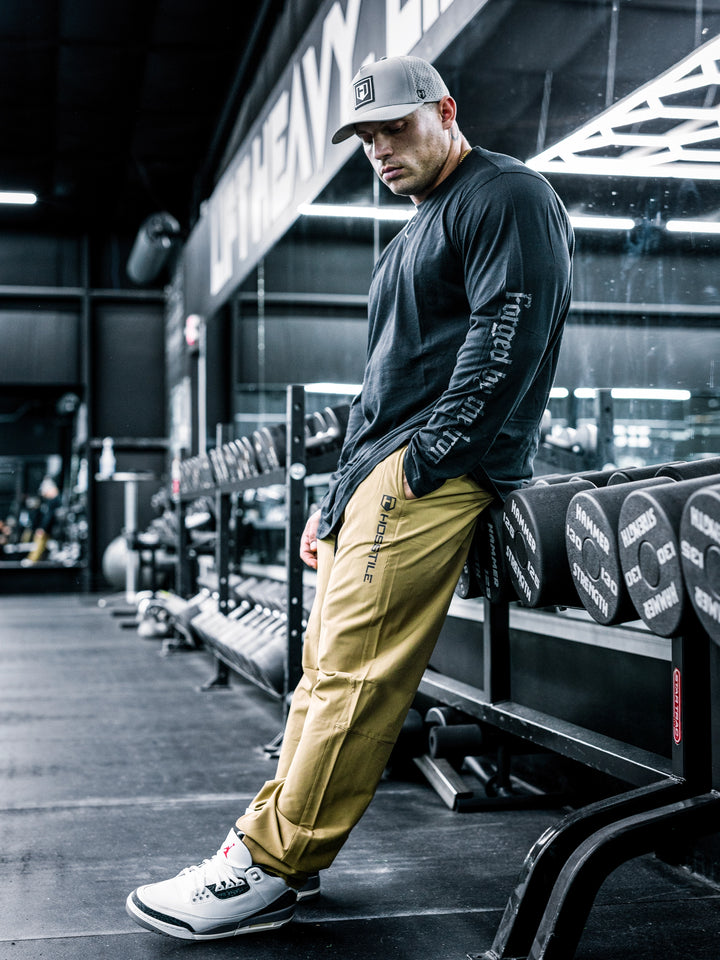 IFBB Pro Bodybuilder Martin Fitzwater wearing a long-sleeve shirt and khaki pants in a gym setting#color_khaki
