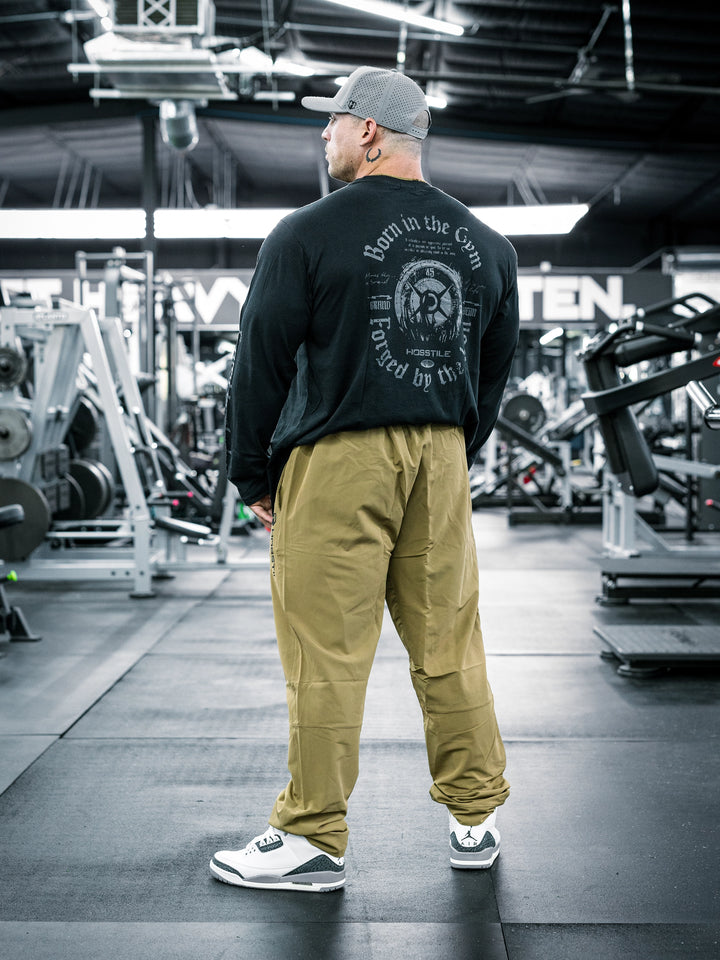 IFBB Pro Bodybuilder Martin Fitzwater wearing a long-sleeve shirt and khaki pants in a gym setting#color_khaki