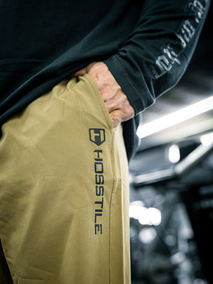 IFBB Pro Bodybuilder Martin Fitzwater wearing a long-sleeve shirt and khaki pants in a gym setting#color_khaki