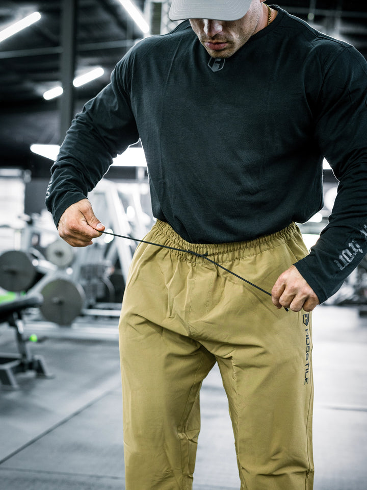 IFBB Pro Bodybuilder Martin Fitzwater wearing a long-sleeve shirt and khaki pants in a gym setting#color_khaki