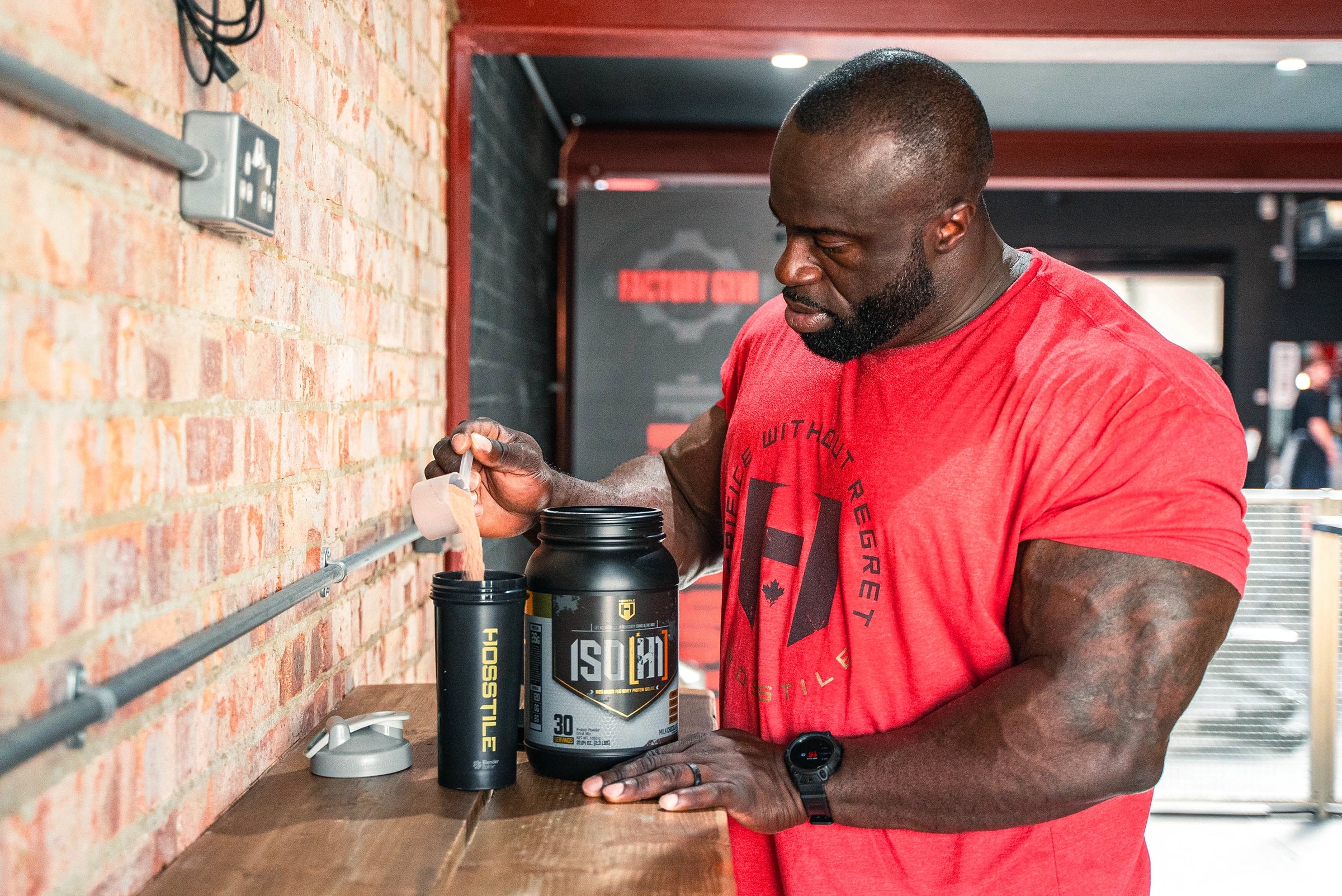 Bodybuilder Samson Dauda scooping Iso protein into shaker cup
