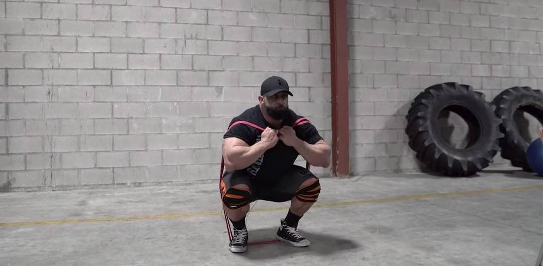 Bodybuilder Fouad Abiad squatting with resistance bands