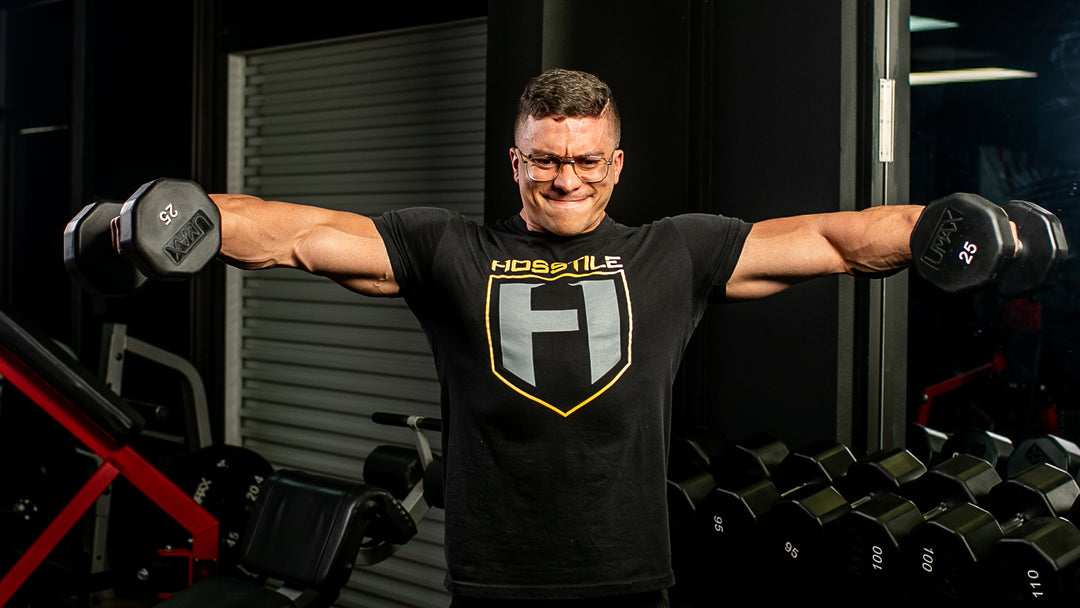 Bodybuilder Logan Guthrie in the gym performing dumbbell lateral raises for shoulders