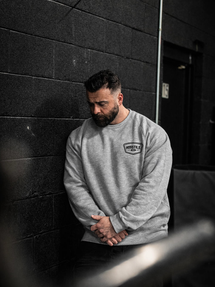 Bodybuilder wearing the Hosstile Club Crew Sweatshirt#color_heather-cement