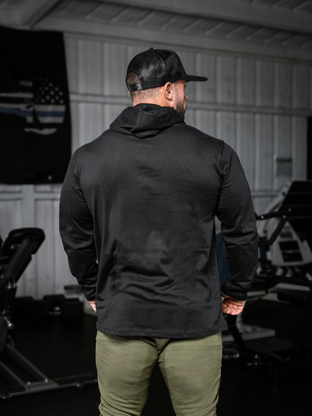 Bodybuilder wearing a lightweight pullover hoodie t-shirt in the gym#color_black