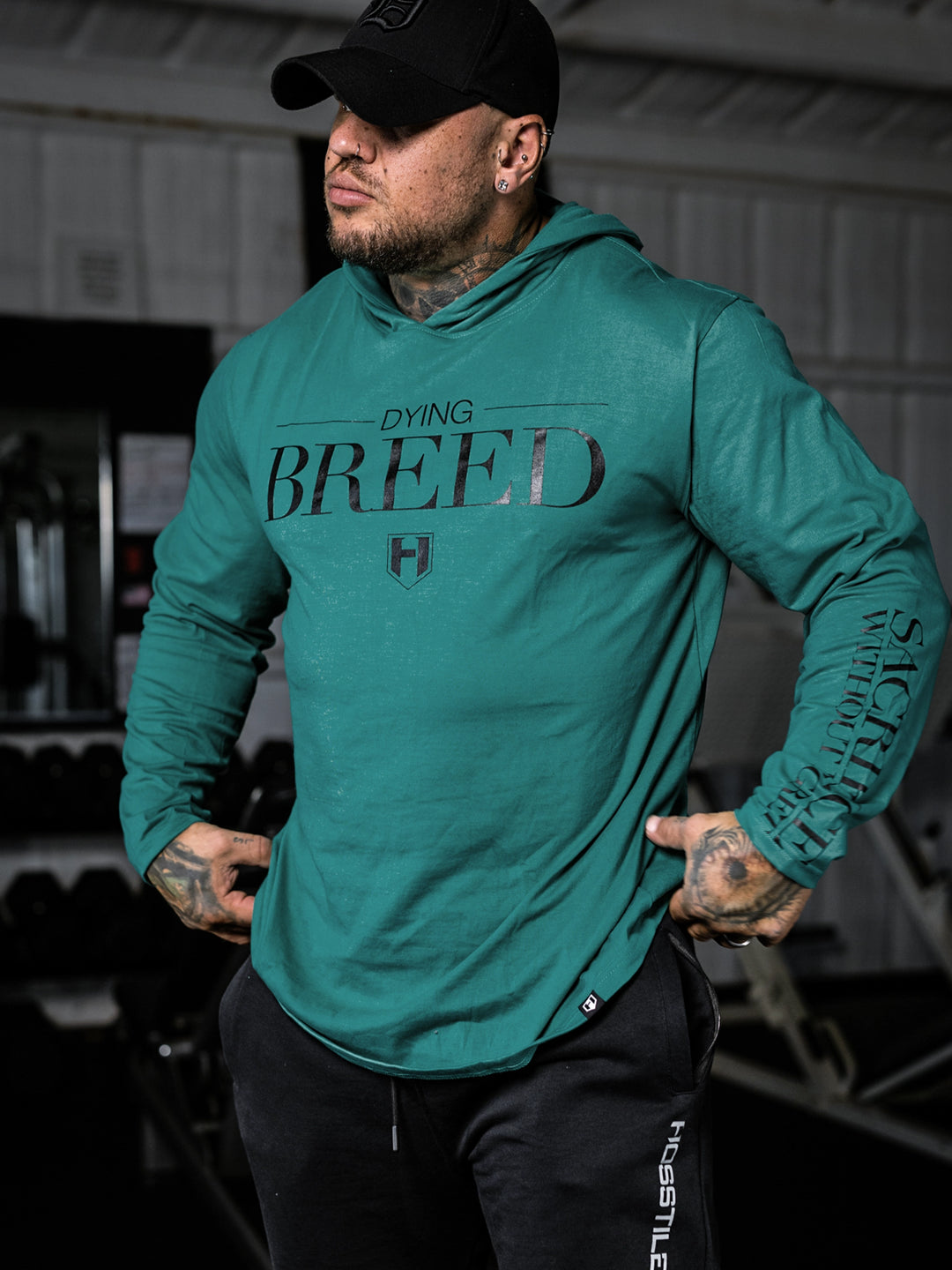 Bodybuilder wearing a lightweight pullover hoodie t-shirt in the gym#color_dark-teal