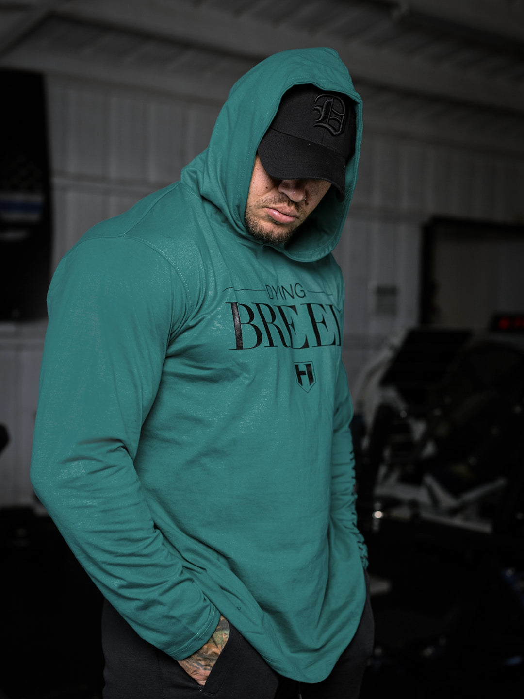 Bodybuilder wearing a lightweight pullover hoodie t-shirt in the gym#color_dark-teal