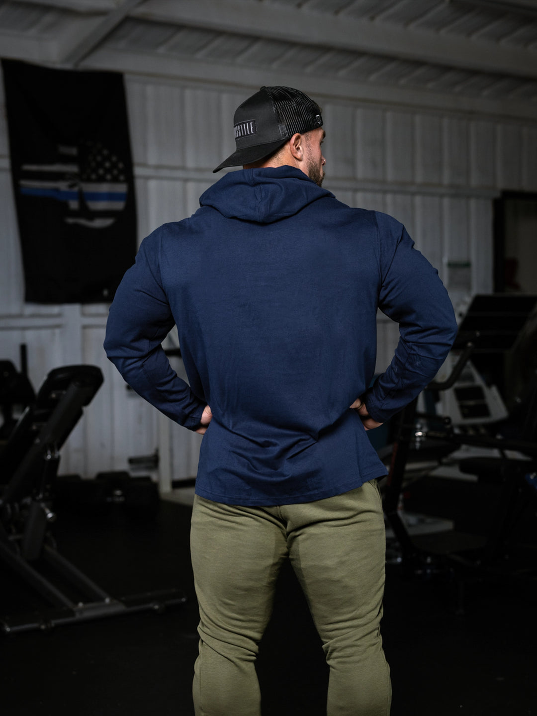 Bodybuilder wearing a lightweight pullover hoodie t-shirt in the gym#color_navy