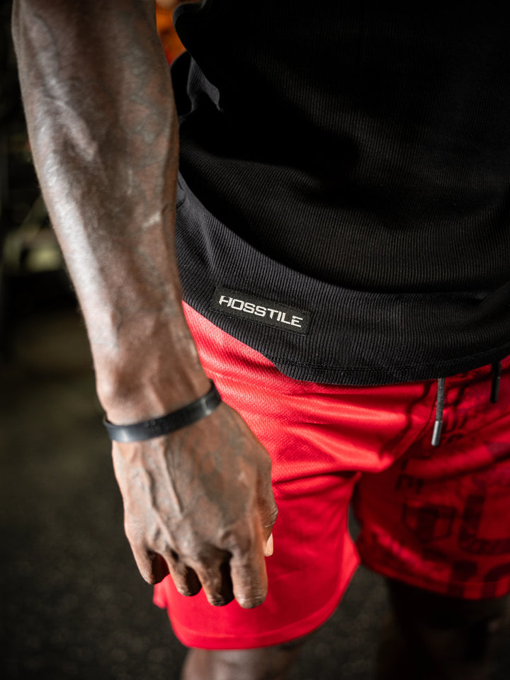 Person wearing a black hoodie with Hosstile branding, red shorts, and a black bracelet#color_black