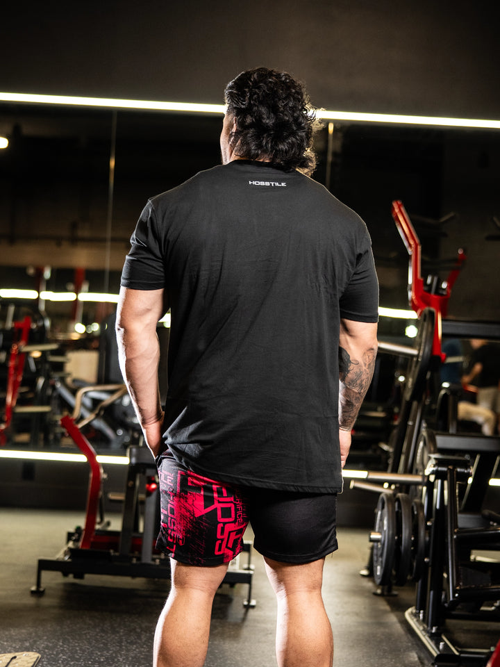 Person wearing a black t-shirt with visible branding in a gym setting#color_black
