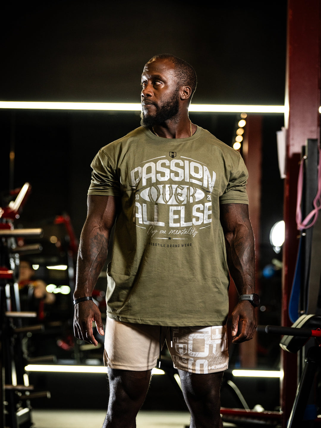 Man wearing a green t-shirt with text in a gym setting#color_military-green
