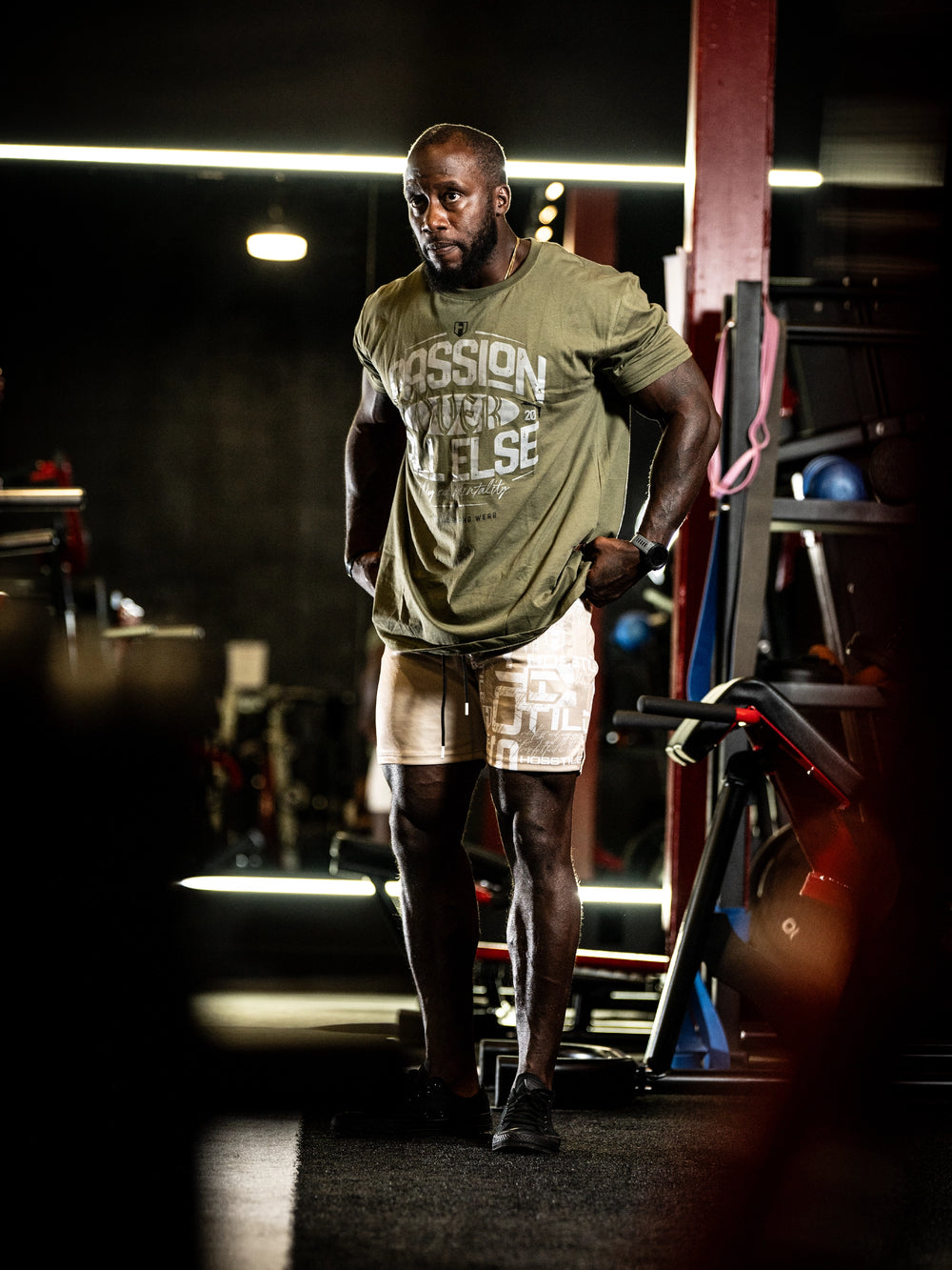 Athlete in a gym wearing a green t-shirt with text and white shorts#color_military-green