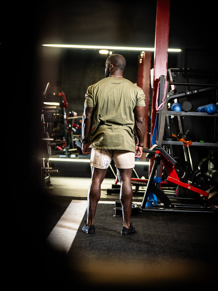 Person in a gym wearing a green shirt and white shorts#color_military-green