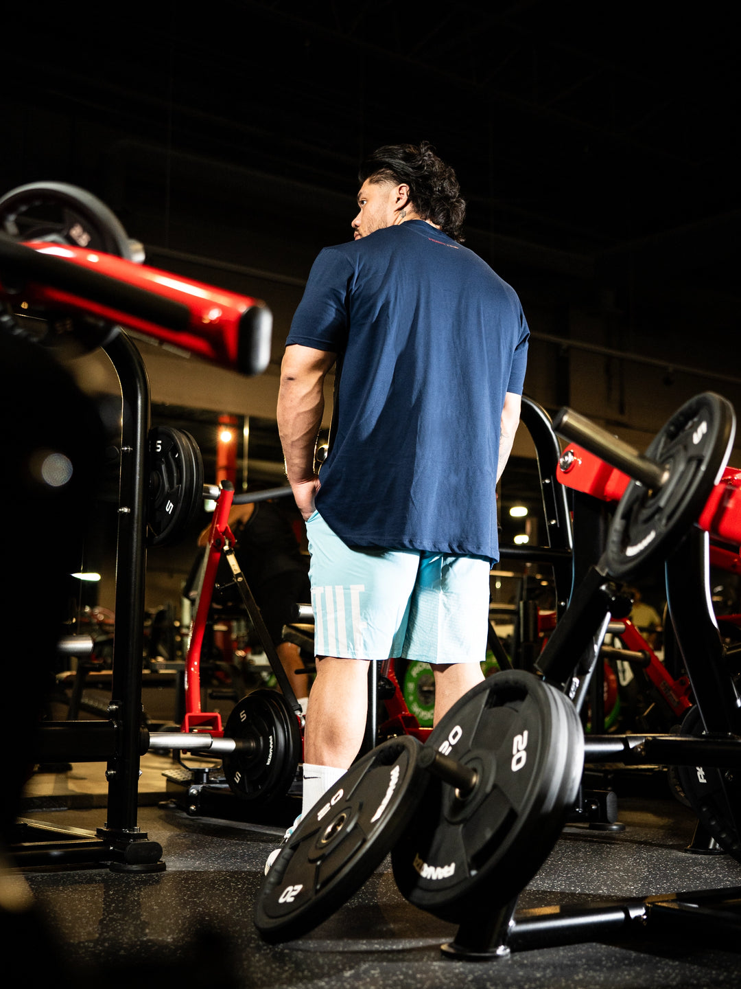 Person in a gym setting with weightlifting equipment#color_navy