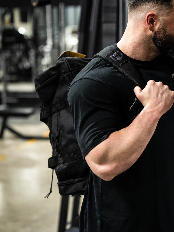 bodybuilder carrying the Hosstile Duffel Backpack in the gym