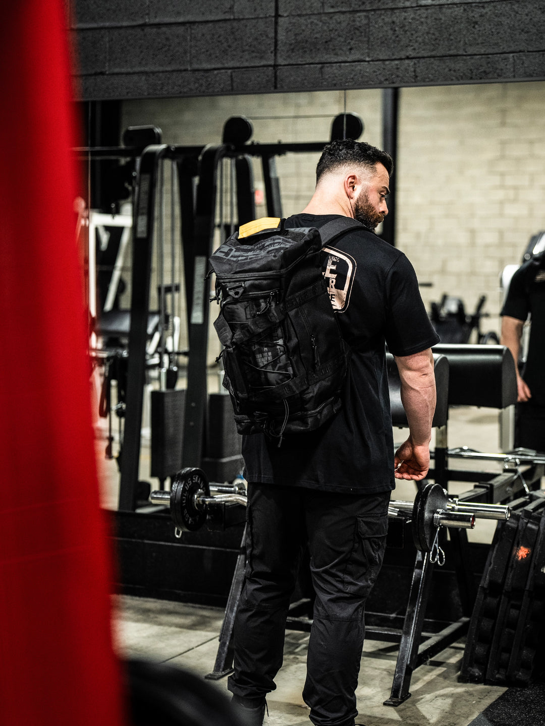 bodybuilder carrying the Hosstile Duffel Backpack in the gym