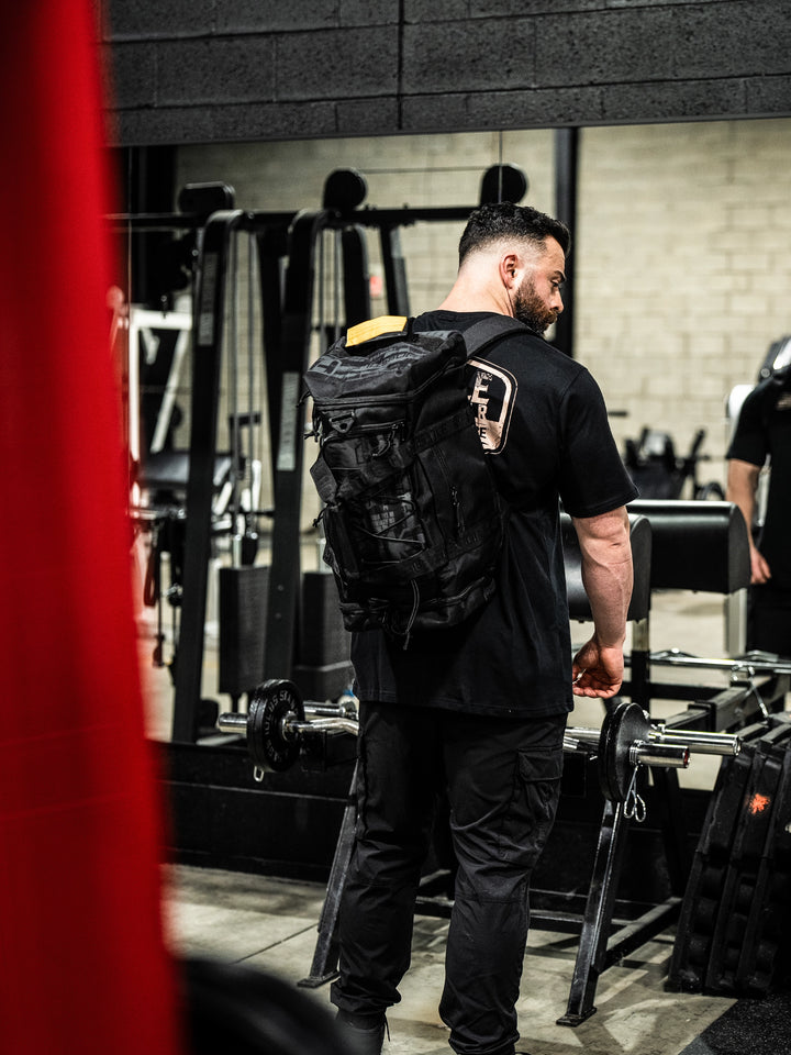 bodybuilder carrying the Hosstile Duffel Backpack in the gym