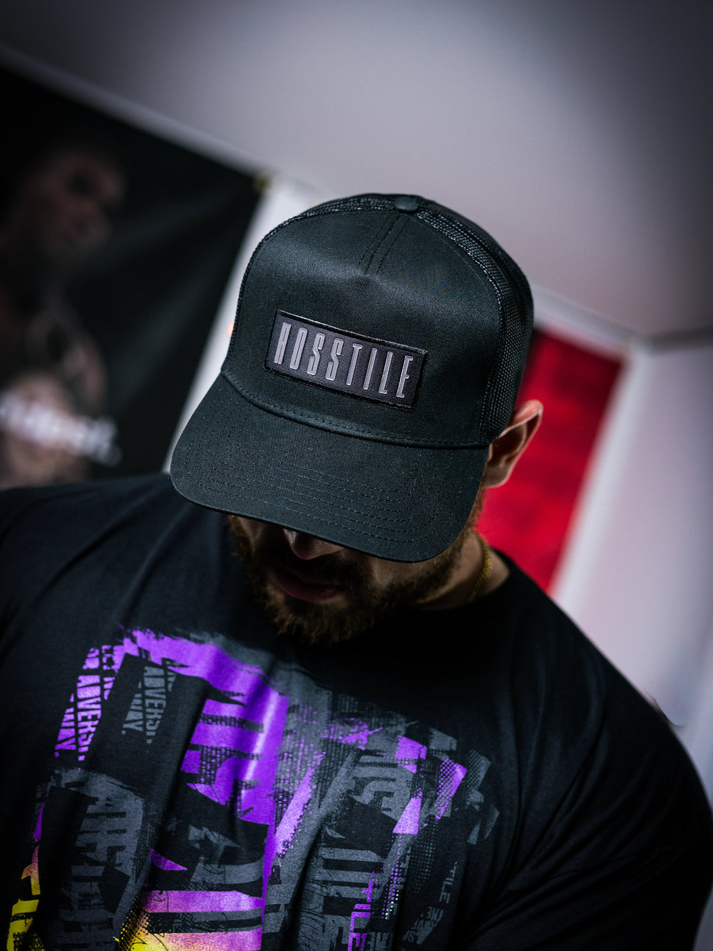 IFBB Martin Fitzwater wearing a black trucker hat with 'Hosstile' logo and a black t-shirt with graphic design.#color_black