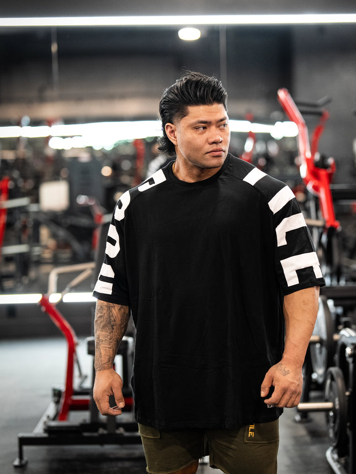 Bodybuilder wearing the Expansion Oversized Tee#color-black
