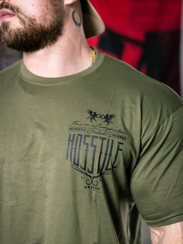 Bodybuilder Martin Fitzwater standing in a gym wearing a t-shirt with text and graphics.#color_military-green