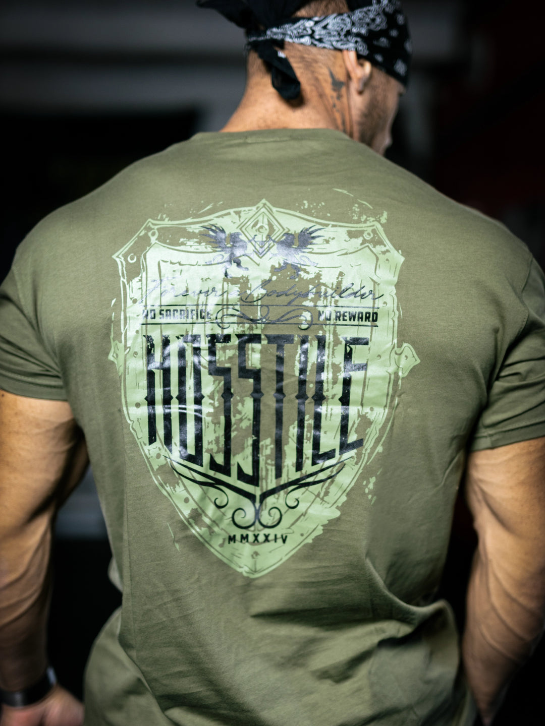 Bodybuilder Ben Chow standing in a gym wearing a t-shirt with text and graphics.#color_military-green