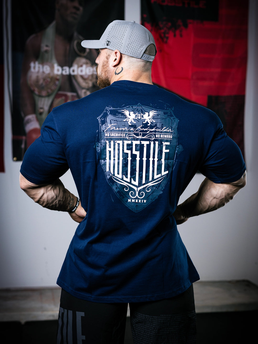 Bodybuilder Martin Fitzwater standing in a gym wearing a t-shirt with text and graphics.#color_navy