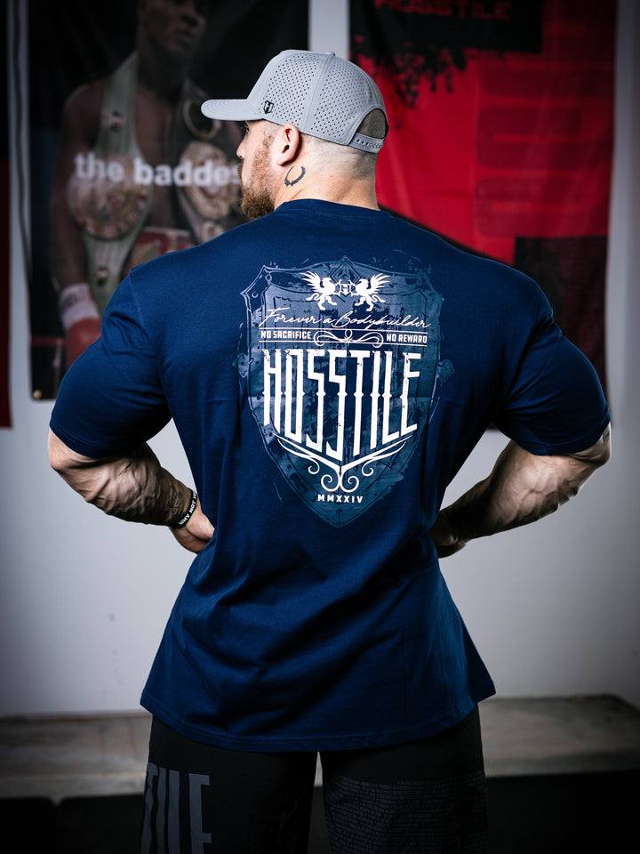 Bodybuilder Martin Fitzwater standing in a gym wearing a t-shirt with text and graphics.#color_navy