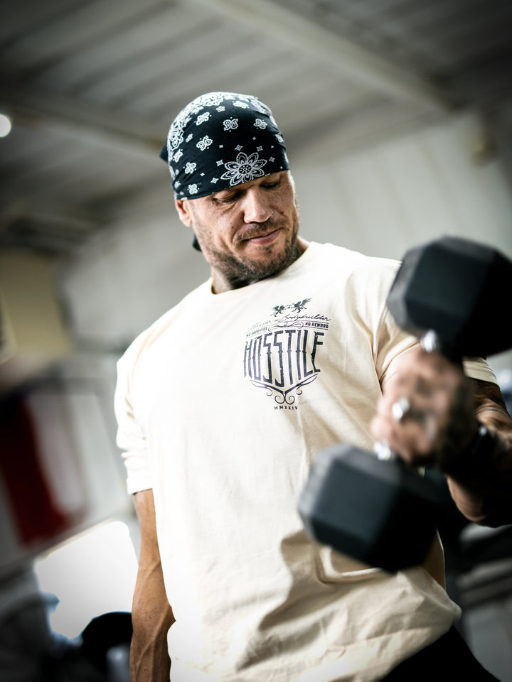 Bodybuilder Ben Chow standing in a gym wearing a t-shirt with text and graphics.#color_off-white