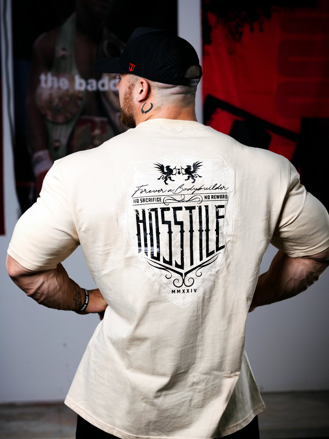 Bodybuilder Martin Fitzwater standing in a gym wearing a t-shirt with text and graphics.#color_off-white