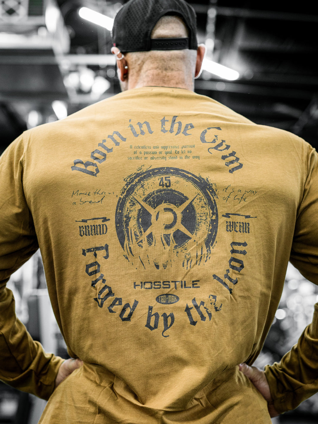 Bodybuilder Ben Chow wearing a black long-sleeve shirt with text in a gym setting#color_texas-clay