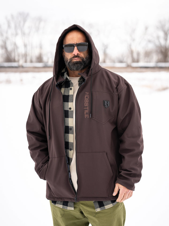 Bodybuilder wearing the Forged Jacket outdoors#color_brown