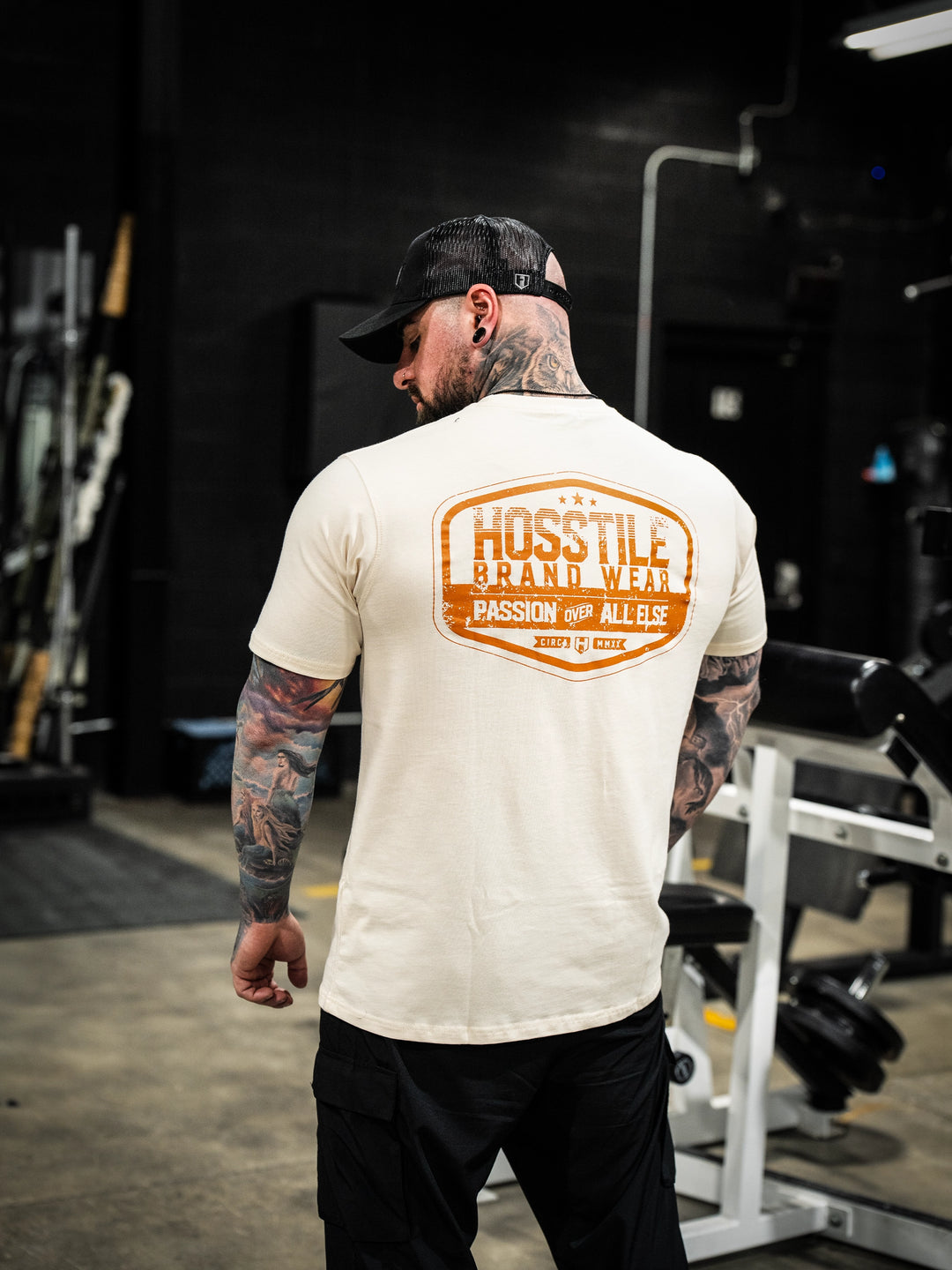 Bodybuilder wearing the Hosstile Garage Tee#color_sand