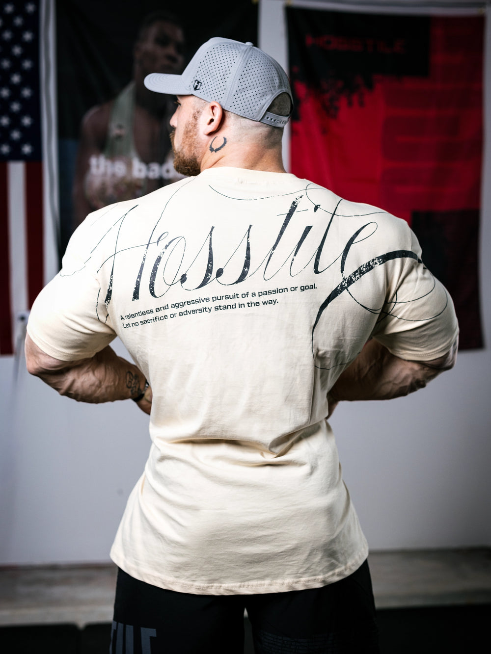Bodybuilder Martin Fitzwater standing in a gym wearing a t-shirt with text and graphics.#color_off-white