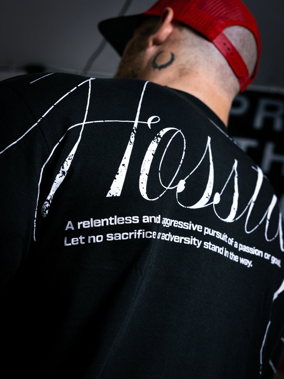 Bodybuilder Martin Fitzwater standing in a gym wearing a t-shirt with text and graphics.#color_black
