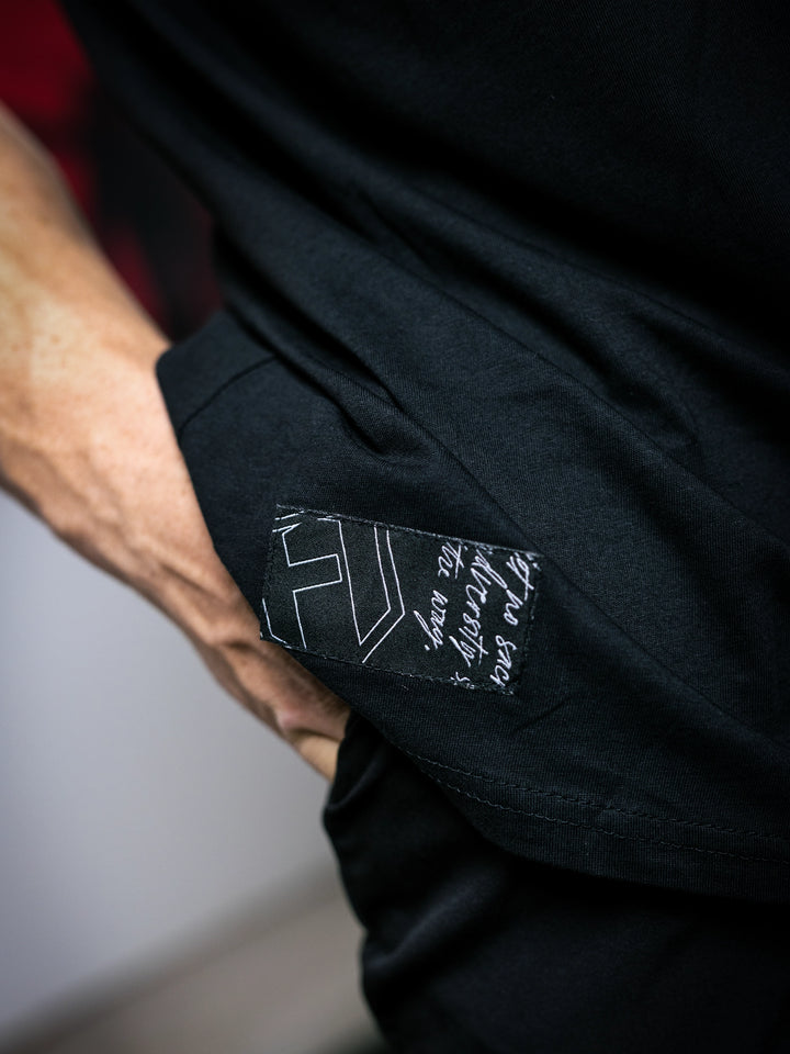 Close-up of a black shirt with a brand label on the sleeve.#color_black
