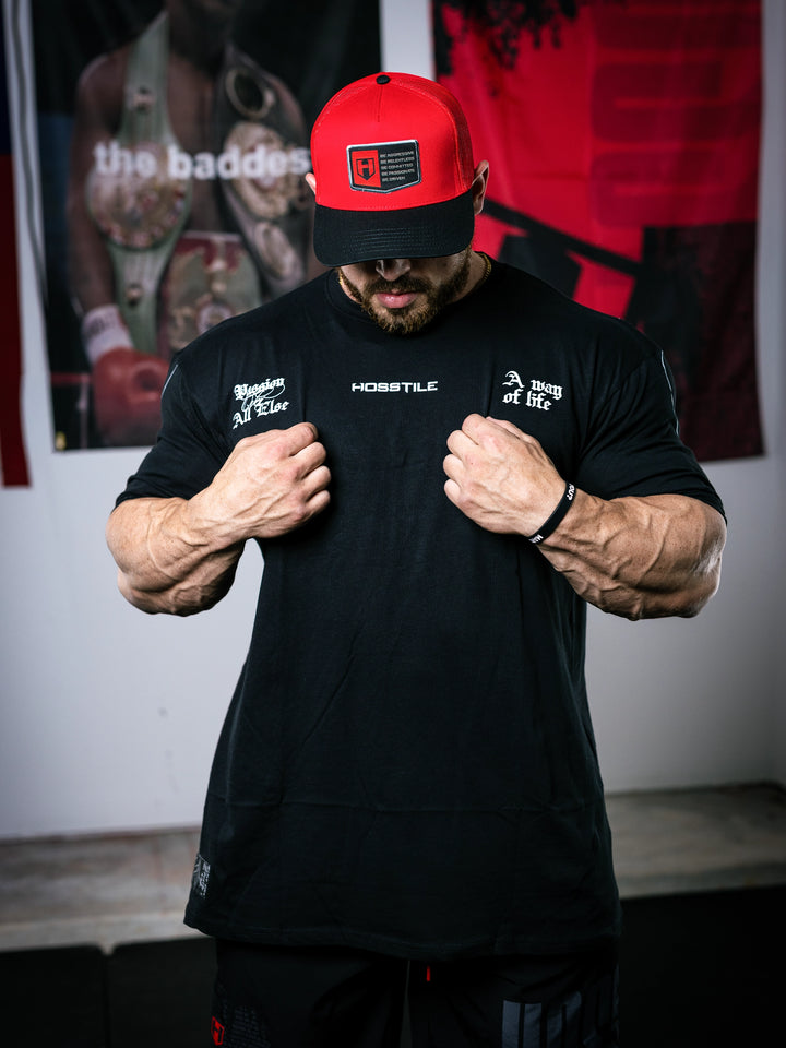 Bodybuilder Martin Fitzwater standing in a gym wearing a t-shirt with text and graphics.#color_black