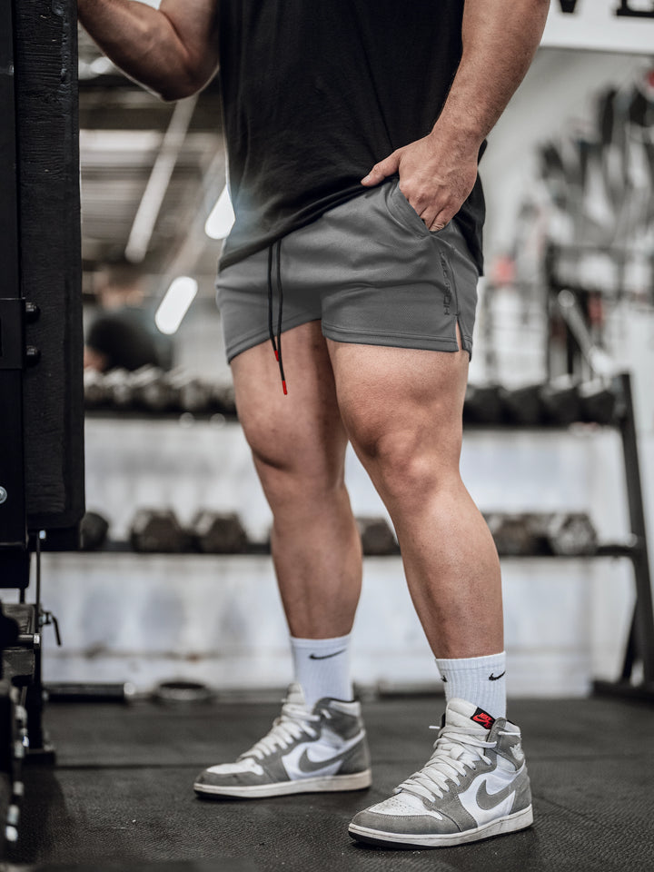 Bodybuilder in gym wearing men's mesh training shorts#color_gunship-grey
