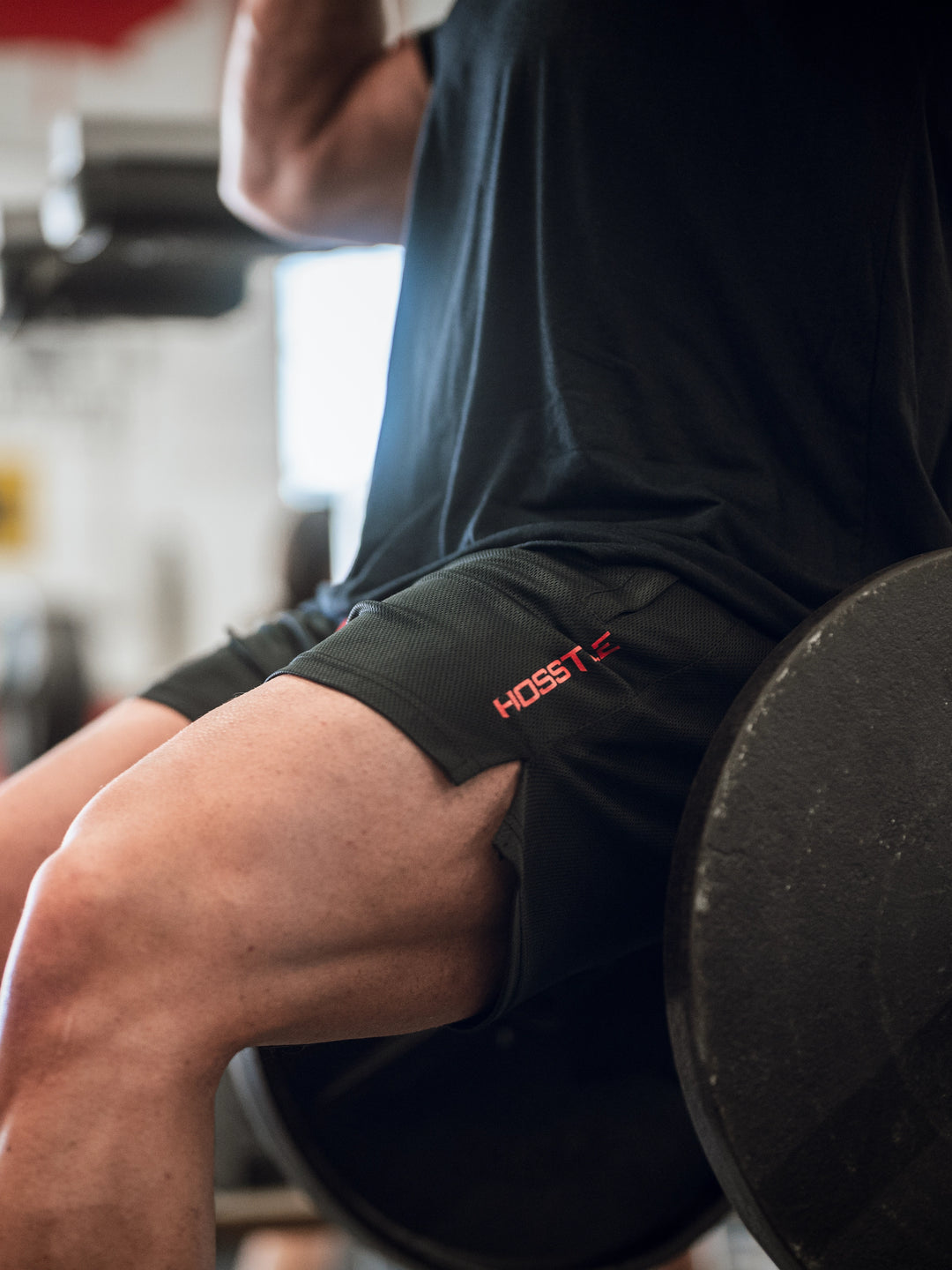 Bodybuilder in gym wearing men's mesh training shorts#color_black-red