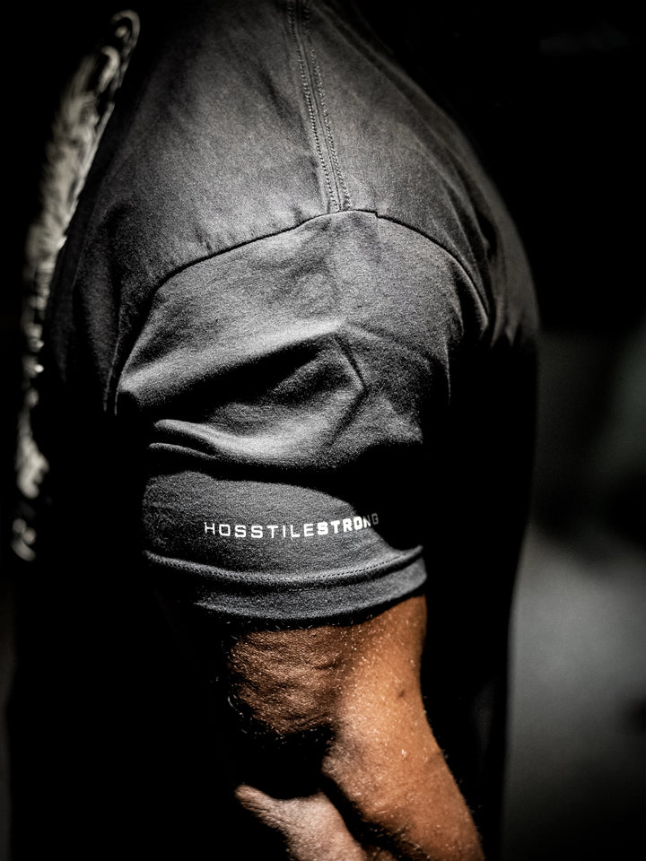 Person wearing a black t-shirt with Hosstile logo on a dark background#color_black