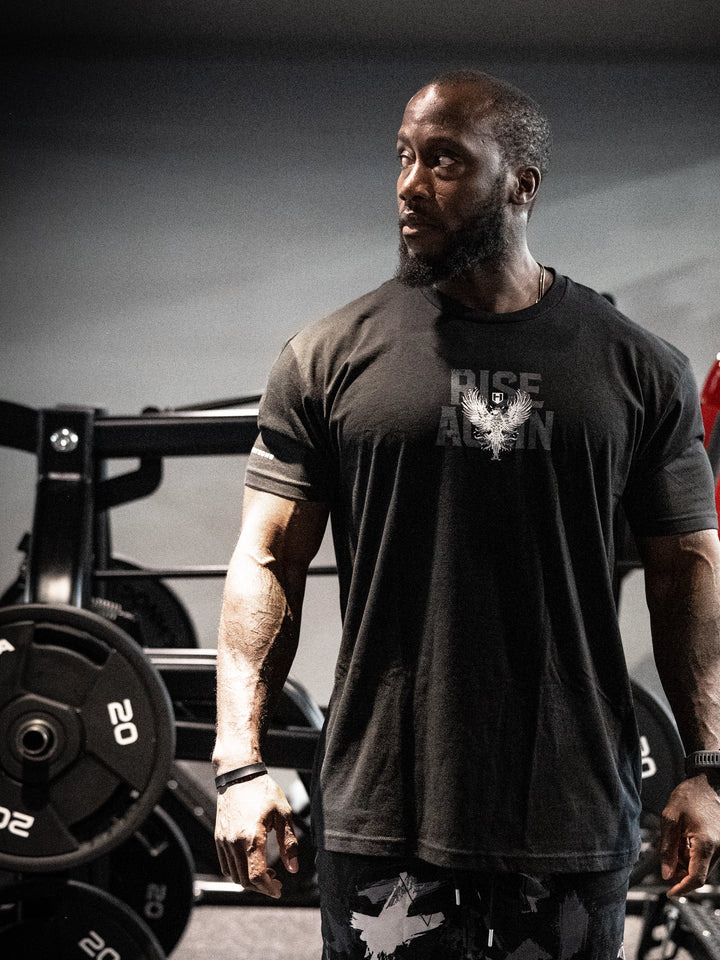 Man wearing a black t-shirt with a logo in a gym setting#color_black
